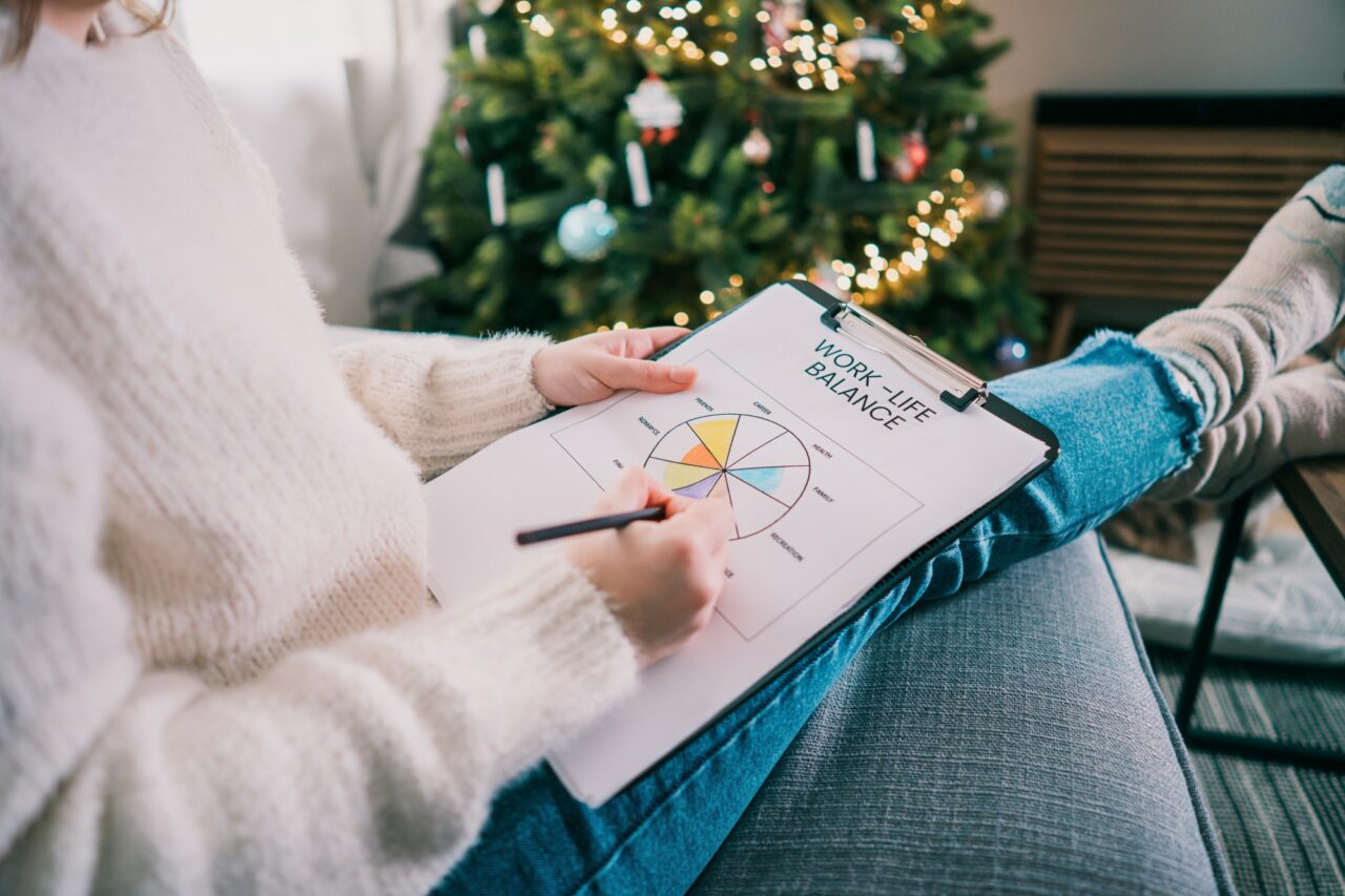 Woman drawing work-life balance wheel sitting on the sofa at home. Self-reflection and life planning. Daily success