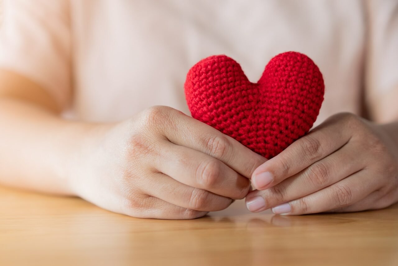 Adult hands holding a yarn red heart
