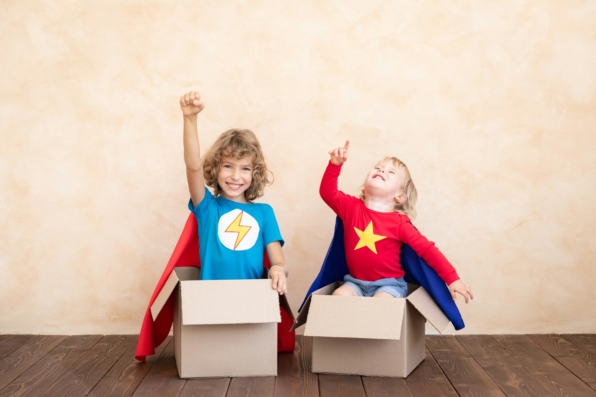 Superheroes children playing in cardboard box
