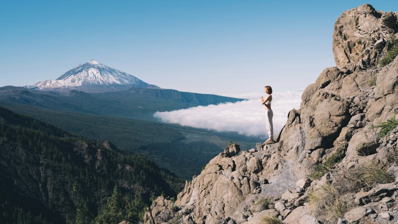Woman doing yoga and meditating on background of natural landscape